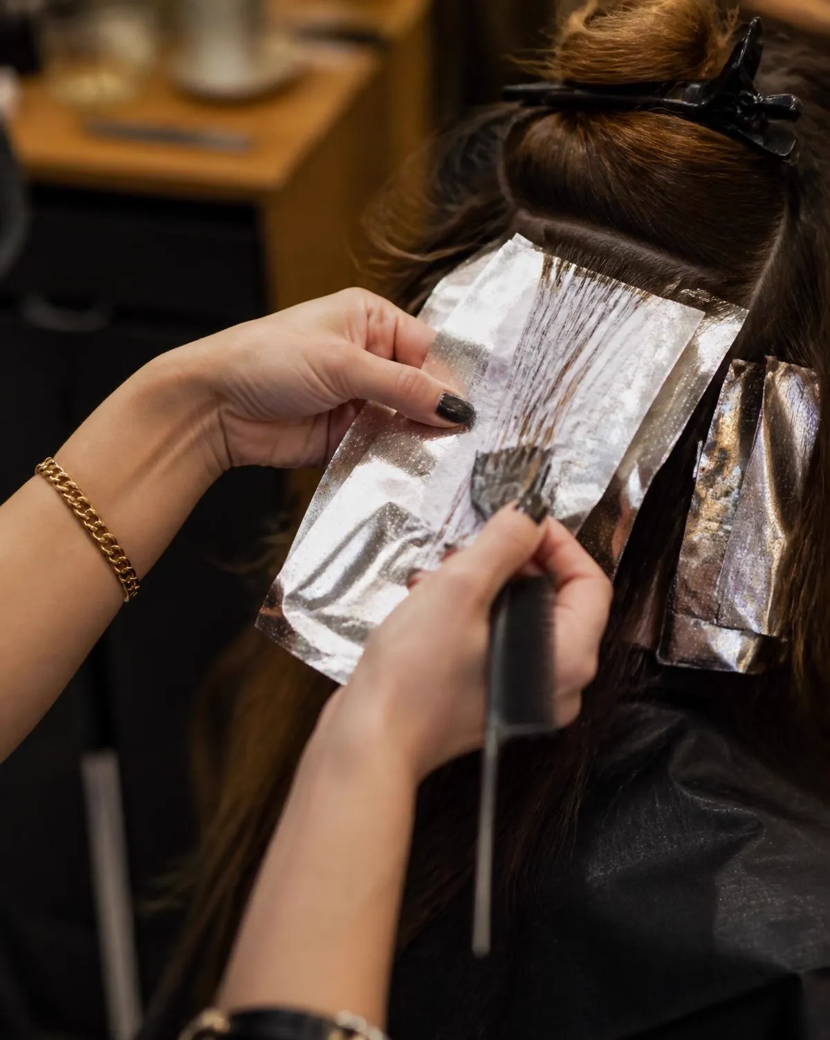 Profissional aplicando mechas no cabelo de uma cliente